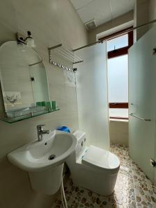 Baño blanco con lavabo y aseo en Alex Home Đà Lạt, en Da Lat