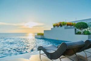 a swimming pool with two chairs and the ocean at C sky Seaview @The Blu X in Bangsaen