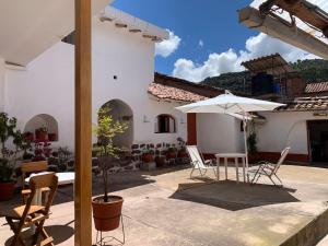 un patio con mesa, sillas y sombrilla en Hospedaje Killipata en Cuzco