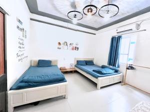 two beds in a room with blue sheets at Domik Homestay - Cát Bà in Cat Ba