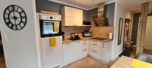 a kitchen with white cabinets and a clock on the wall at Ferienwohnung am Bibelgarten Julia in Werlte