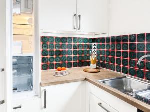 a kitchen with white cabinets and black tiles on the wall at Reihenendhaus Marina Sol in Dahme