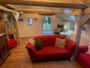 ein Wohnzimmer mit einem roten Sofa und einem Fenster in der Unterkunft Landhaus up Diek in Wittmund