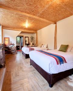 two beds in a room with wooden ceilings at Spirit Of The River Lodge in Cusco