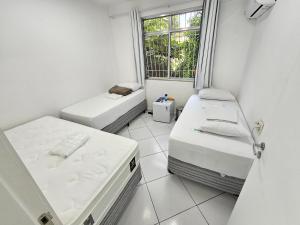 um pequeno quarto com 2 camas e uma janela em Quarto Privativo em Condominio no Rio de Janeiro