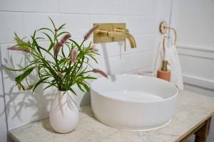 a white sink and a vase with flowers on a counter at Clementine Cottage in Crows Nest