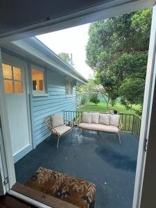 a porch with a couch and two chairs on it at Clementine Cottage in Crows Nest