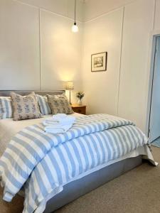 1 dormitorio con 1 cama con rayas azules y blancas en Clementine Cottage en Crows Nest