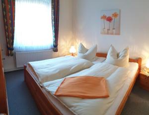 a bedroom with a bed with white sheets and a window at Ferienhof Manowski Nr1 in Hinrichsdorf