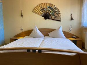 ein Bett mit weißer Bettwäsche und einer Uhr an der Wand in der Unterkunft Ferienwohnung Blessbergblick in Eisfeld