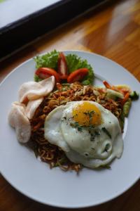 a white plate of food with an egg on top at Balong Balong Surf Bungalows & Restaurant in Sekongkang