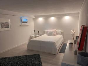 a white bedroom with a white bed and a window at Charmante Einliegerwohnung, 3 Zimmer in ruhiger Wohnlage, 60qm, mit gemütlicher Südterrasse in Hahnerheide