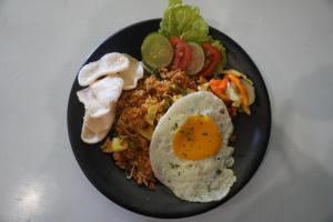 un plato negro de comida con un huevo y verduras en Balong Balong Surf Bungalows & Restaurant en Sekongkang