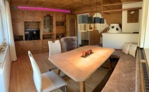 comedor con mesa de madera y sillas blancas en Komfortables Ferienhaus in Landeck mit Privatem Pool, en Landeck