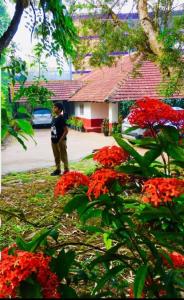 Un homme debout à côté d'une bande de fleurs rouges dans l'établissement Coorg Daffodil Guesthouse, à Madikeri