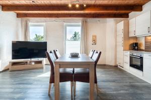 a kitchen with a table with chairs and a television at Nr 1 Meerhusen - Barrierefrei in Aurich