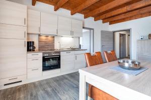 a kitchen with white cabinets and a wooden table at Nr 1 Meerhusen - Barrierefrei in Aurich
