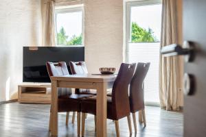 a dining room table with chairs and a television at Nr 1 Meerhusen - Barrierefrei in Aurich +17 photos