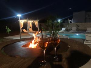 dos copas de vino sentadas en una mesa junto al fuego en B&B Casa Karina Pool&Rooms, en Specchia
