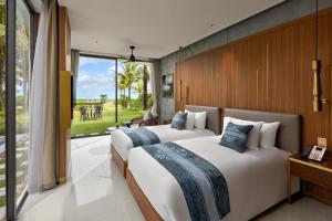 two beds in a hotel room with a large window at Wyndham Hoi An Royal Beachfront Resort & Villas in Hoi An