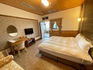 een slaapkamer met een bed, een bureau en een televisie bij Dragon Manor Resort in Renai