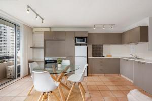 eine Küche mit einem Glastisch und weißen Stühlen in der Unterkunft Hi Ho Beach Apartments on Broadbeach in Gold Coast
