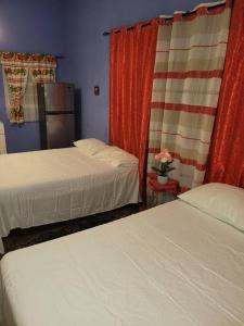 Country Style living في Albion: غرفة فندقية بسريرين وستائر حمراء