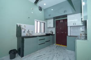 una cucina con armadietti bianchi e una porta rossa di Katyayani Serenity - Your Premium Homestay a Bhadrachalam