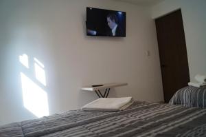 1 dormitorio con 1 cama y TV en la pared en Centro Expositor, Feria, Estadios, Planetario #4, en Puebla