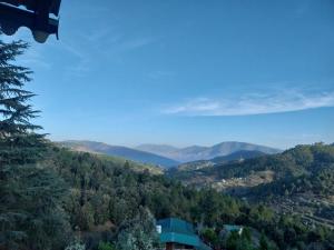 vistas a un valle con montañas a lo lejos en Anmol paradise en Mukteswar