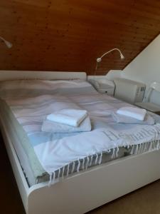 ein weißes Bett mit zwei weißen Handtüchern darauf in der Unterkunft Haus am Bodden in Fuhlendorf