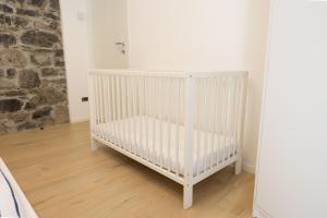 - un lit bébé blanc dans une chambre dotée d'un mur en pierre dans l'établissement Il Giglio - Free Parking, à Côme
