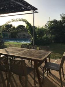 una mesa de madera con 4 sillas y una sombrilla en maison 3 chambres avec piscine en Calvi