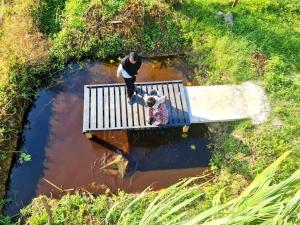 two people standing on a wooden bridge in the water at Panorama Indah Homestay in Sungai Besar