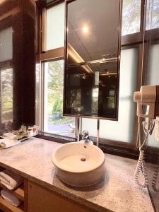 a bathroom with a sink and a large mirror at Lake Mountain View Hotel in Hsinchu City