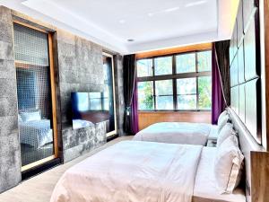 two beds in a room with windows and a tv at Lake Mountain View Hotel in Hsinchu City
