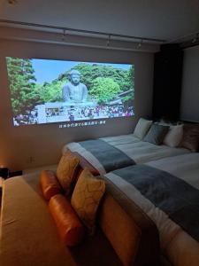 two beds in a room with a large screen at Tre casa hotel KAMAKURA in Kamakura