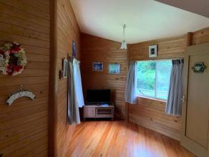 a room with wooden walls and a television and a window at ilca イルカの家 -Kumano Kodo Nagaizaka- in Susami +7 photos