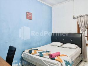 1 dormitorio con 1 cama con pared azul en Lafa Park Syariah Mitra RedDoorz en Glonggong