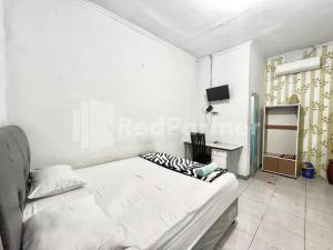 a white bedroom with a bed and a desk at Lafa Park Syariah Mitra RedDoorz in Glonggong