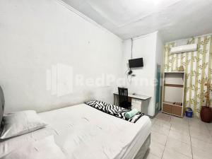 a white bedroom with a bed and a television at Lafa Park Syariah Mitra RedDoorz in Glonggong