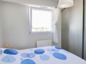 um quarto com uma cama azul e branca e uma janela em Appartement Saint-Jean-de-Monts, 2 pièces, 4 personnes - FR-1-323-255 em Saint-Jean-de-Monts