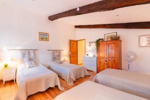 a bedroom with two beds and a dresser at l'Oeil de Carcassonne in Caudebronde