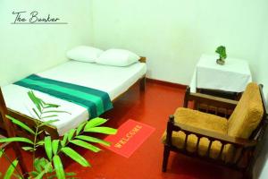 a room with a bed and a chair and a table at The Bunker in Badulla