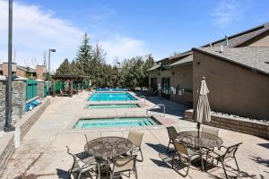a pool with tables and chairs next to a building at Stylish and Modern Park Ave Condo, Swimming Pool, 5 minutes to Main in Park City