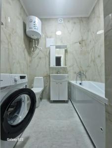 a bathroom with a washing machine and a sink at Квартира Достар in Karagandy