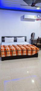 een slaapkamer met een bed met een oranje geruite deken bij Priya Prem peeth guest house ⁰ in Vrindāvan