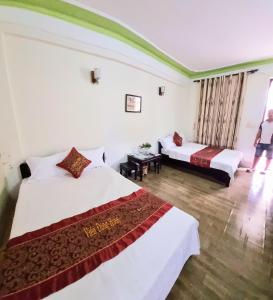 une chambre d'hôtel avec deux lits et une femme debout dans la fenêtre dans l'établissement Khách sạn Viễn Đông, à Dong Quan