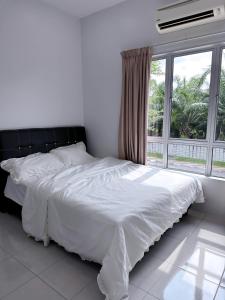 - un lit blanc dans une chambre avec une grande fenêtre dans l'établissement Homestay, à Sitiawan