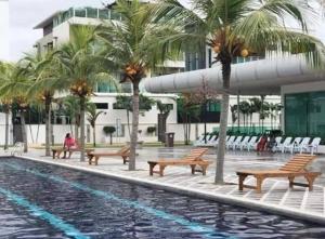 une piscine avec bancs et palmiers à côté d'un bâtiment dans l'établissement Homestay, à Sitiawan